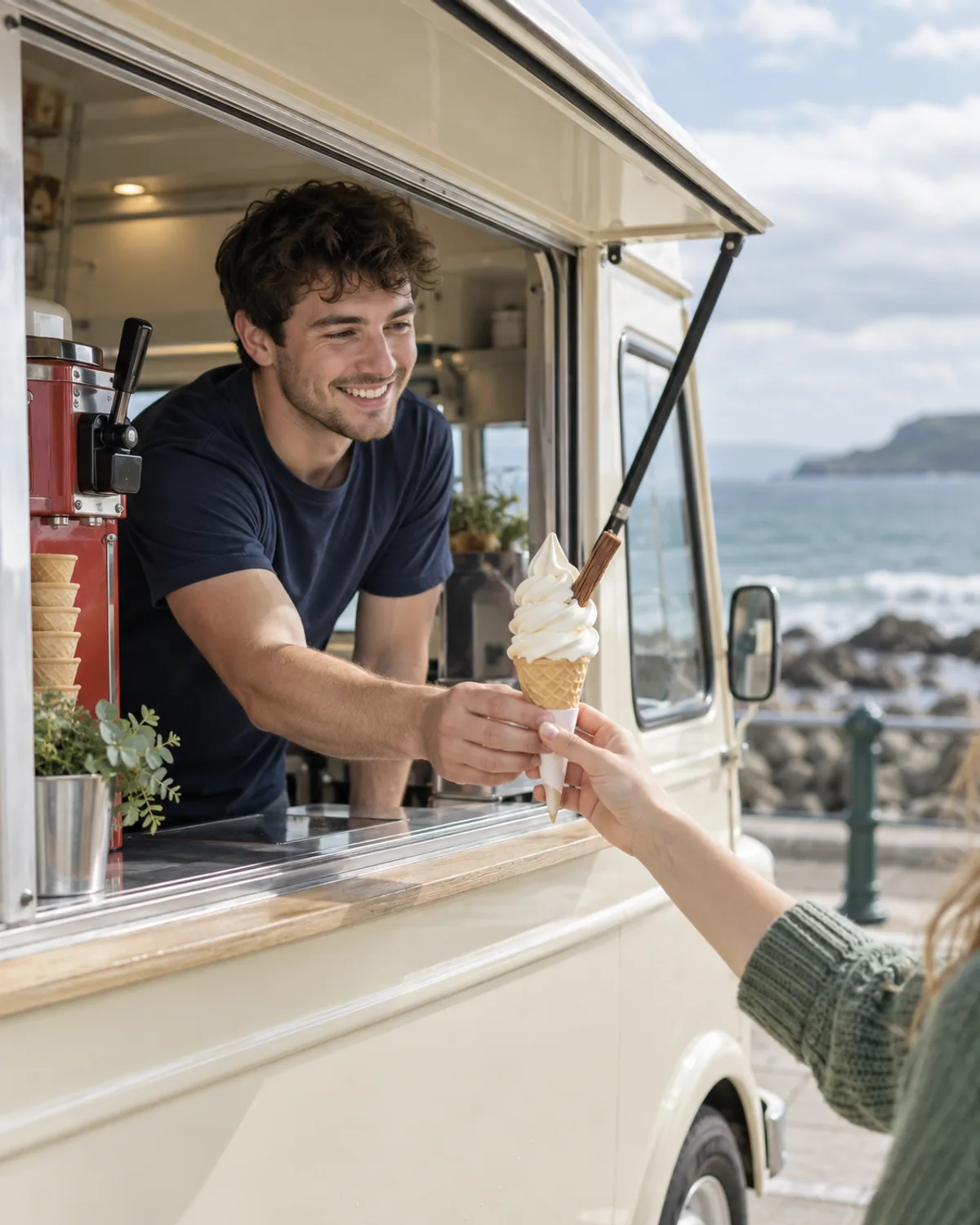 Ice cream van owner passing a cone through the hatch by the sea